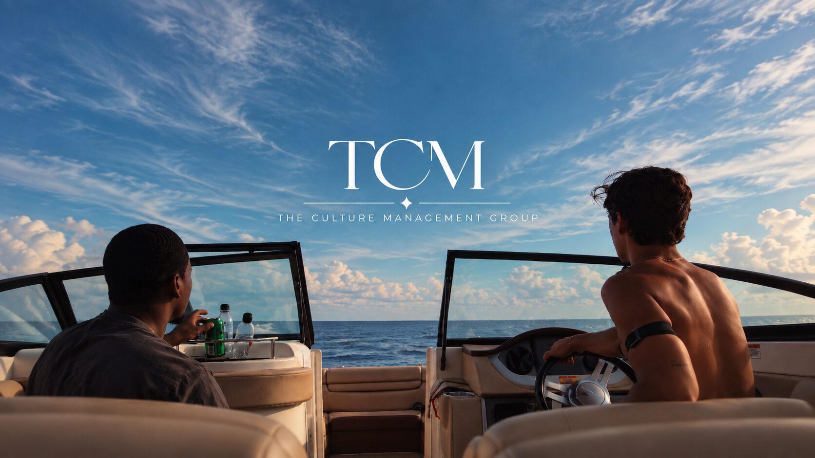 Two TCM clients on a boat heading out to open water under a blue sky with The Culture Management Group logo